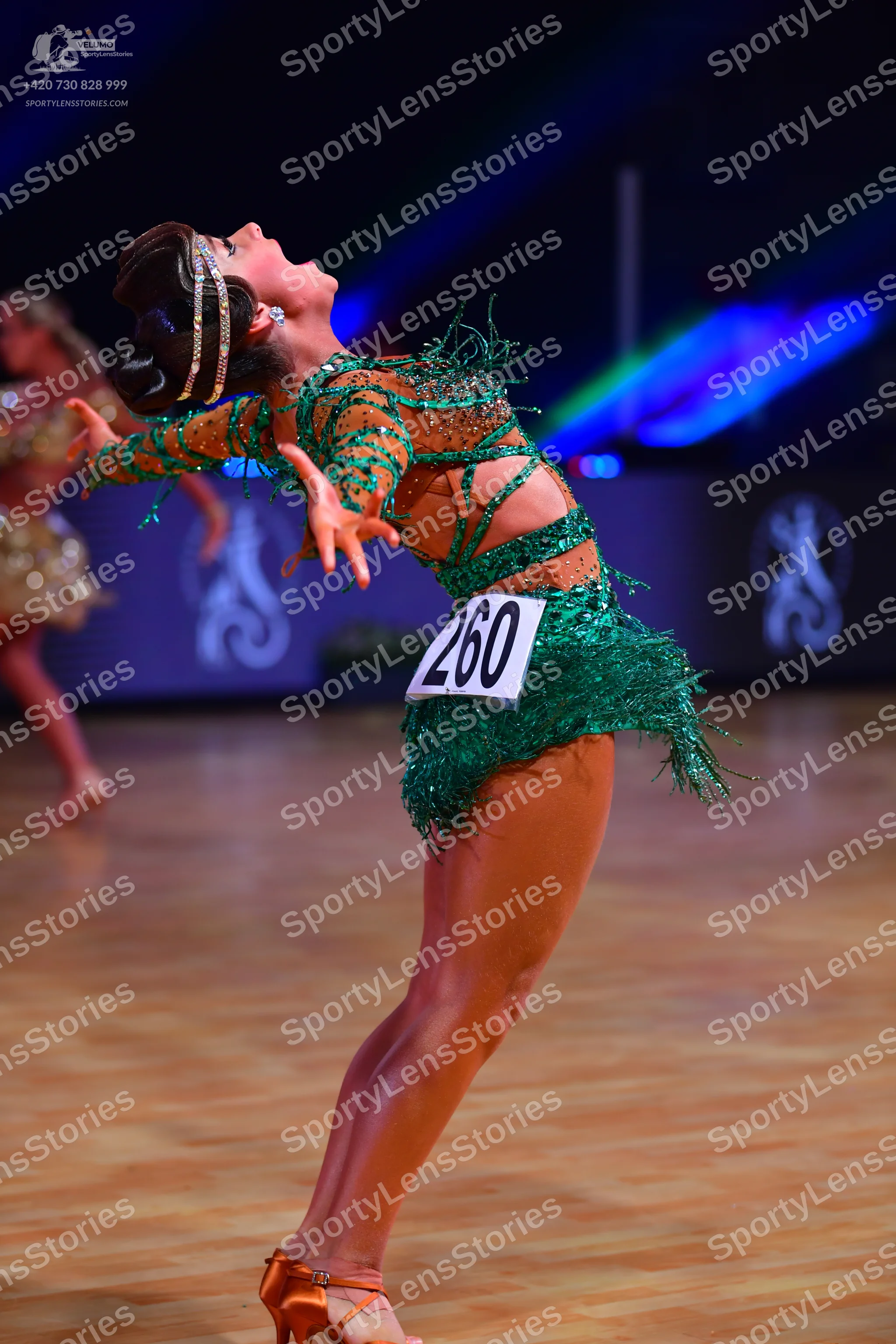 Dancesport competitor: Female dancer in foreground: emerald green sequin latin dress with cut-out detai