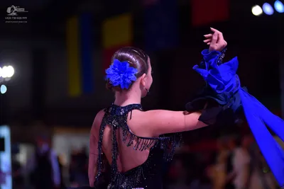 Dancesport competitor: Female dancer: black latin dress with sequins and fringe, featuring a large blue