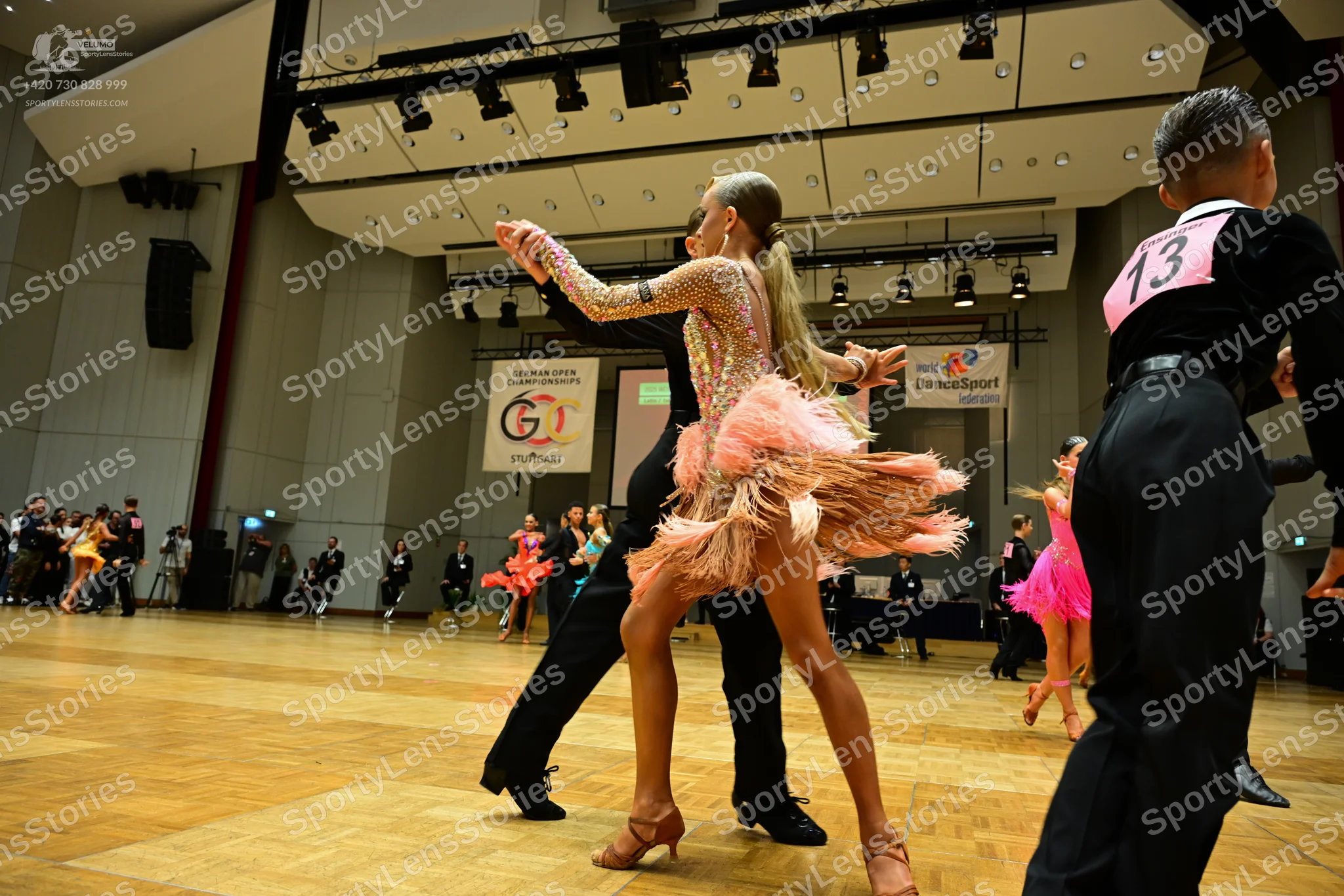 Dancesport competitor #13: Male dancer (foreground right): black long-sleeved shirt with pink number 13 and