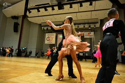 Dancesport competitor #13: Male dancer (foreground right): black long-sleeved shirt with pink number 13 and