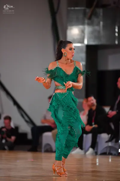 Dancesport competitor: Female dancer: emerald green latin dance dress with thin straps, a cutout at the