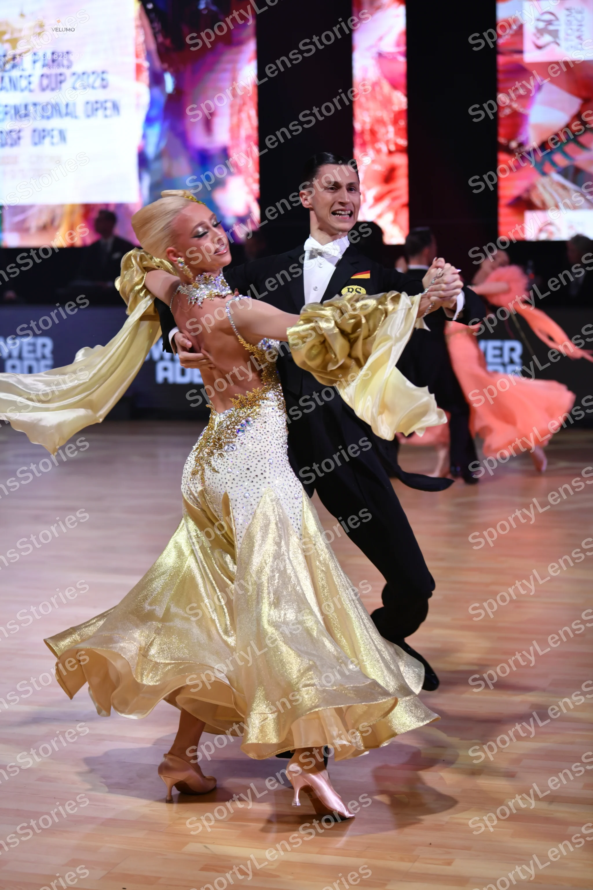 Dancesport competitor: Female dancer: shimmering gold ballroom dress with a heavily embellished bodice