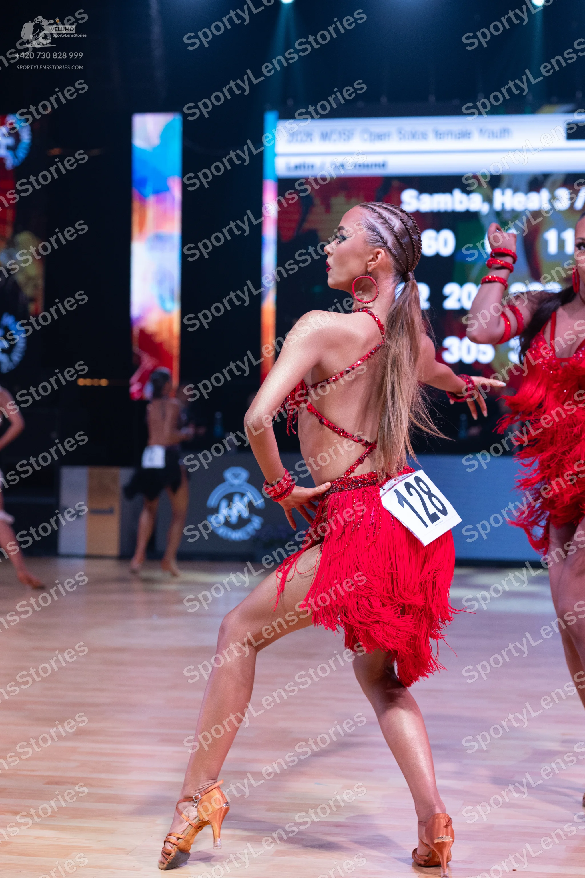 Dancesport competitor: Female dancer in foreground: red latin dress with fringe