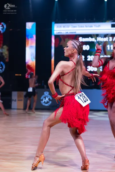 Dancesport competitor: Female dancer in foreground: red latin dress with fringe