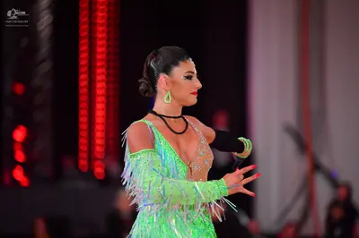 Dancesport competitor: Female dancer: lime green Latin dress with sequins and long fringe, nude-colored