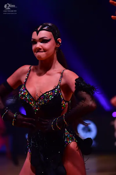 Dancesport competitor: Female dancer: black latin dress heavily embellished with multi-colored sequins 