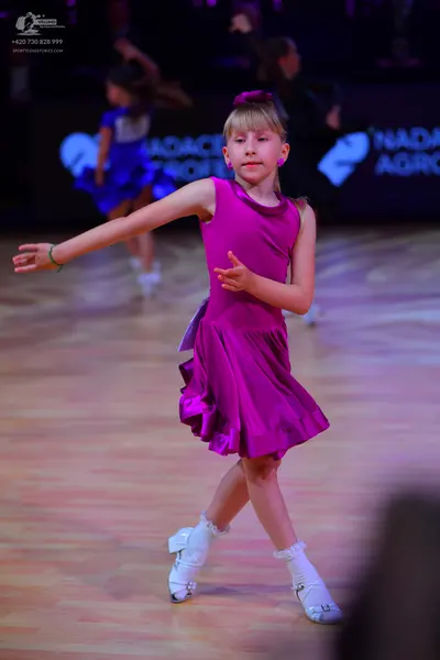 Dancesport competitor: Female dancer: bright magenta/purple satin Latin dress with a flared skirt, whit