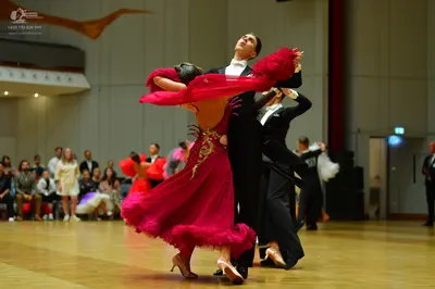 Dancesport competitor: Female dancer: red/magenta Latin dress with flowing ruffles and gold embellishme