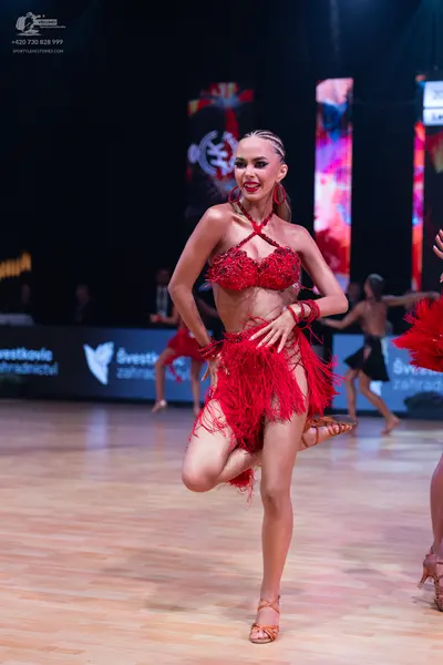 Dancesport competitor: Female dancer in foreground: red Latin dance costume consisting of a halter-neck