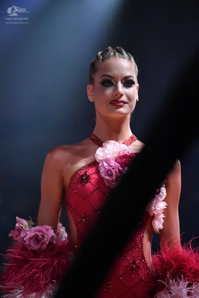 Dancesport competitor: Female dancer: red/pink Latin dress with a diamond pattern, sequins, large flora