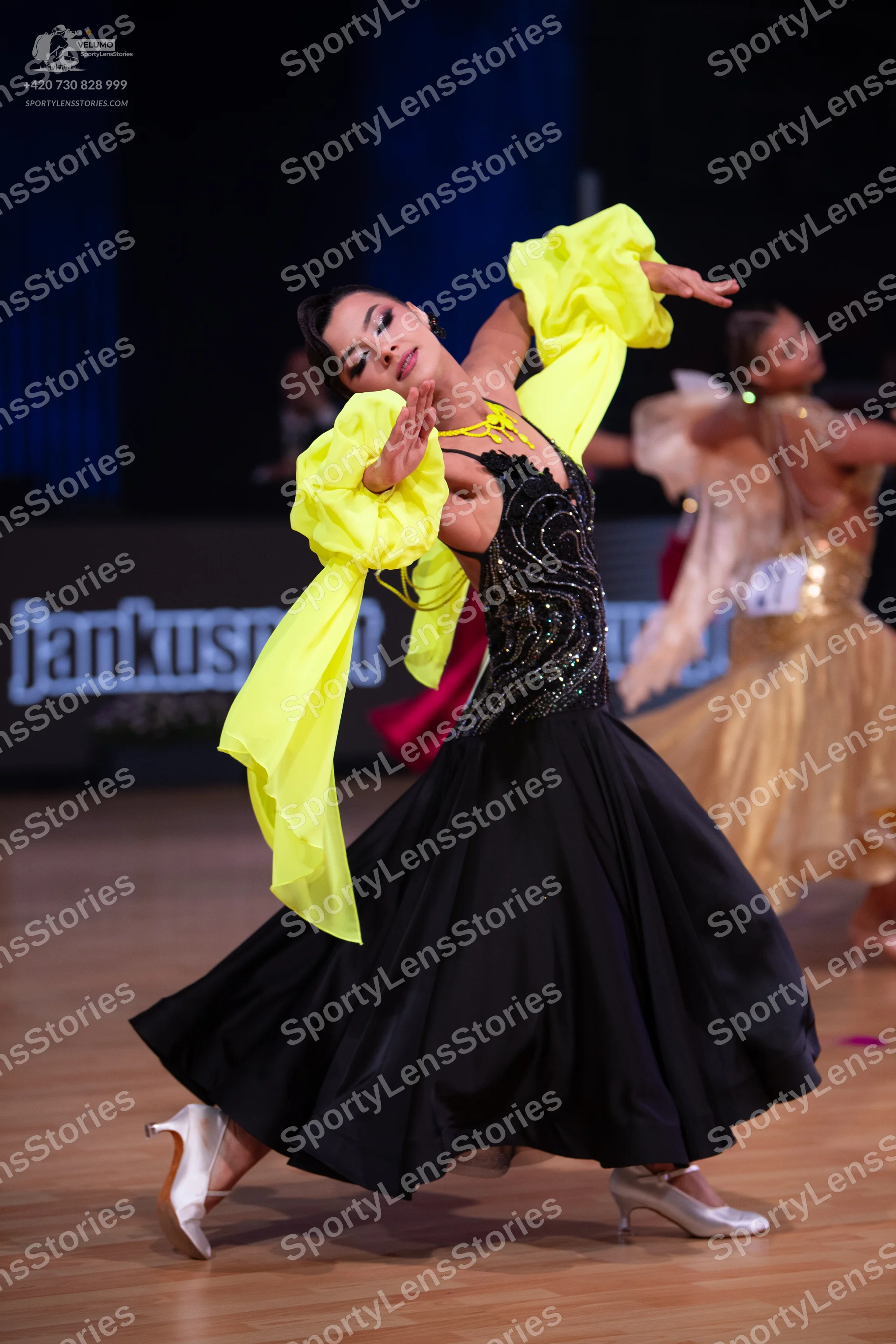 Dancesport competitor: Female dancer: black ballgown with a sequined bodice and large, flowing, bright