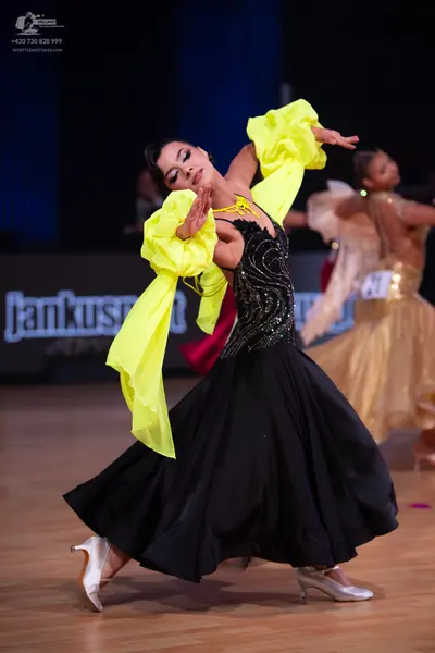 Dancesport competitor: Female dancer: black ballgown with a sequined bodice and large, flowing, bright 