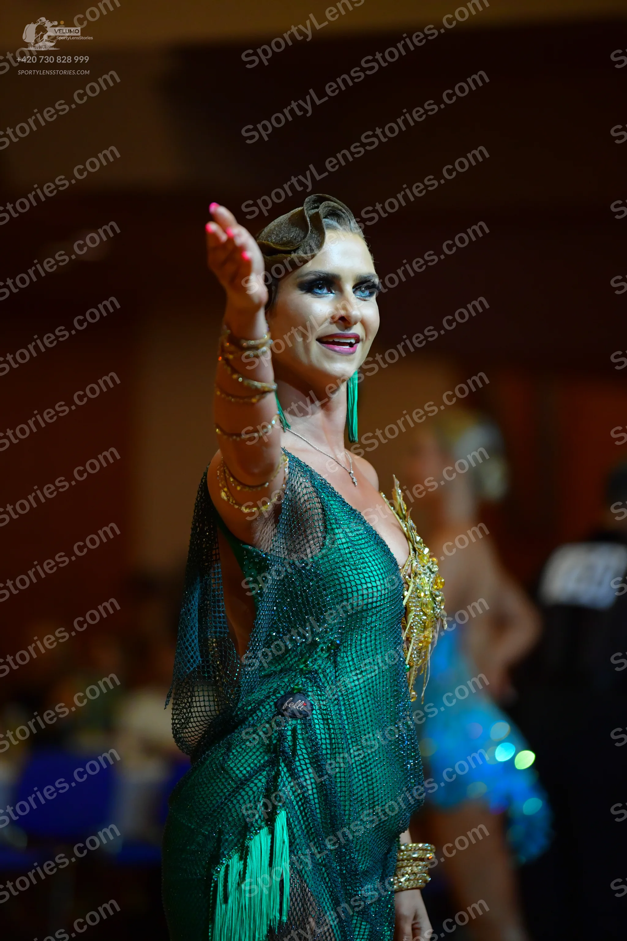 Dancesport competitor: Female dancer in foreground: green latin dress made of mesh fabric with fringe, 