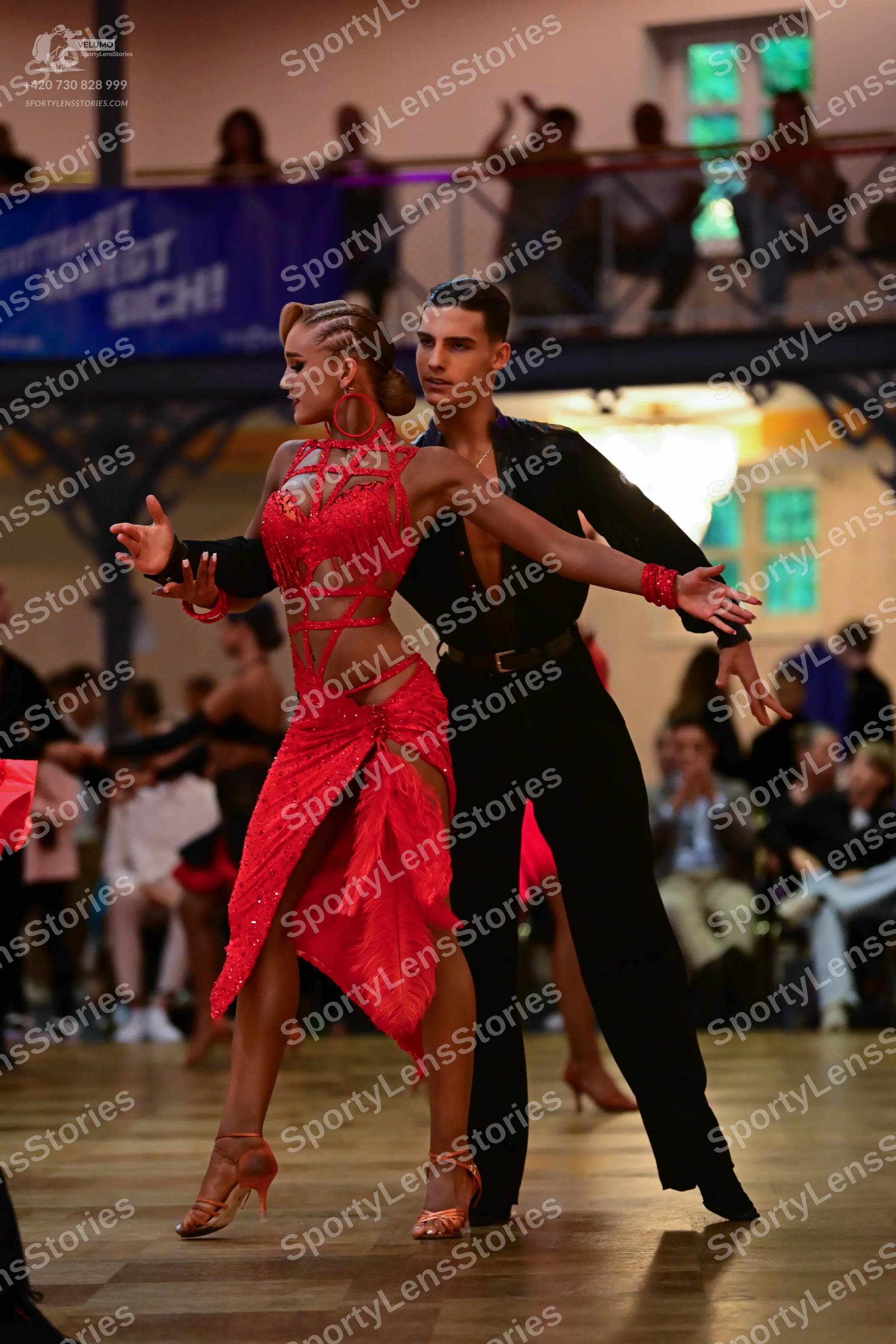 Dancesport competitor: Female dancer: red latin dress with intricate red lace/embellishments, featuring