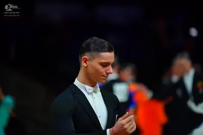 Dancesport competitor: Male dancer in foreground: black suit, white shirt, and white bow tie