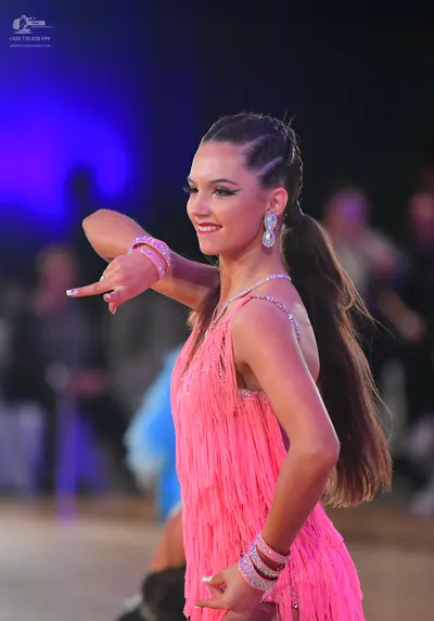 Dancesport competitor: Female dancer: pink Latin dress with long fringe, embellished straps, and multip