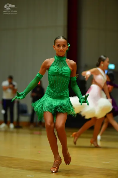 Dancesport competitor: Female dancer 1: green Latin dress with long sleeves and a fringed skirt