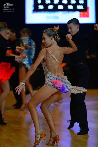 Dancesport competitor: Main female dancer: nude-colored Latin dance dress with gold, pink, and purple s