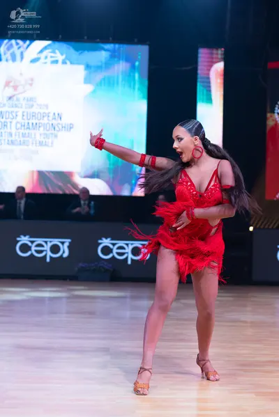 Dancesport competitor: Female dancer: red latin dress with fringe and sequins, red hoop earrings, and r