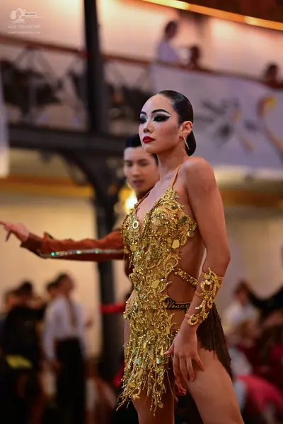 Dancesport competitor: Female dancer: gold latin dress with intricate sequin and beadwork, featuring fr