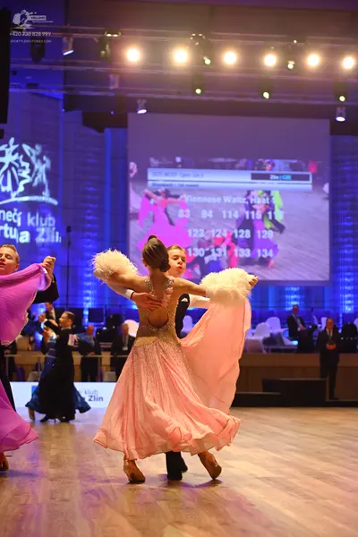 Dancesport competitor: Main female dancer: peach-colored ballgown with a sequined bodice and white feat
