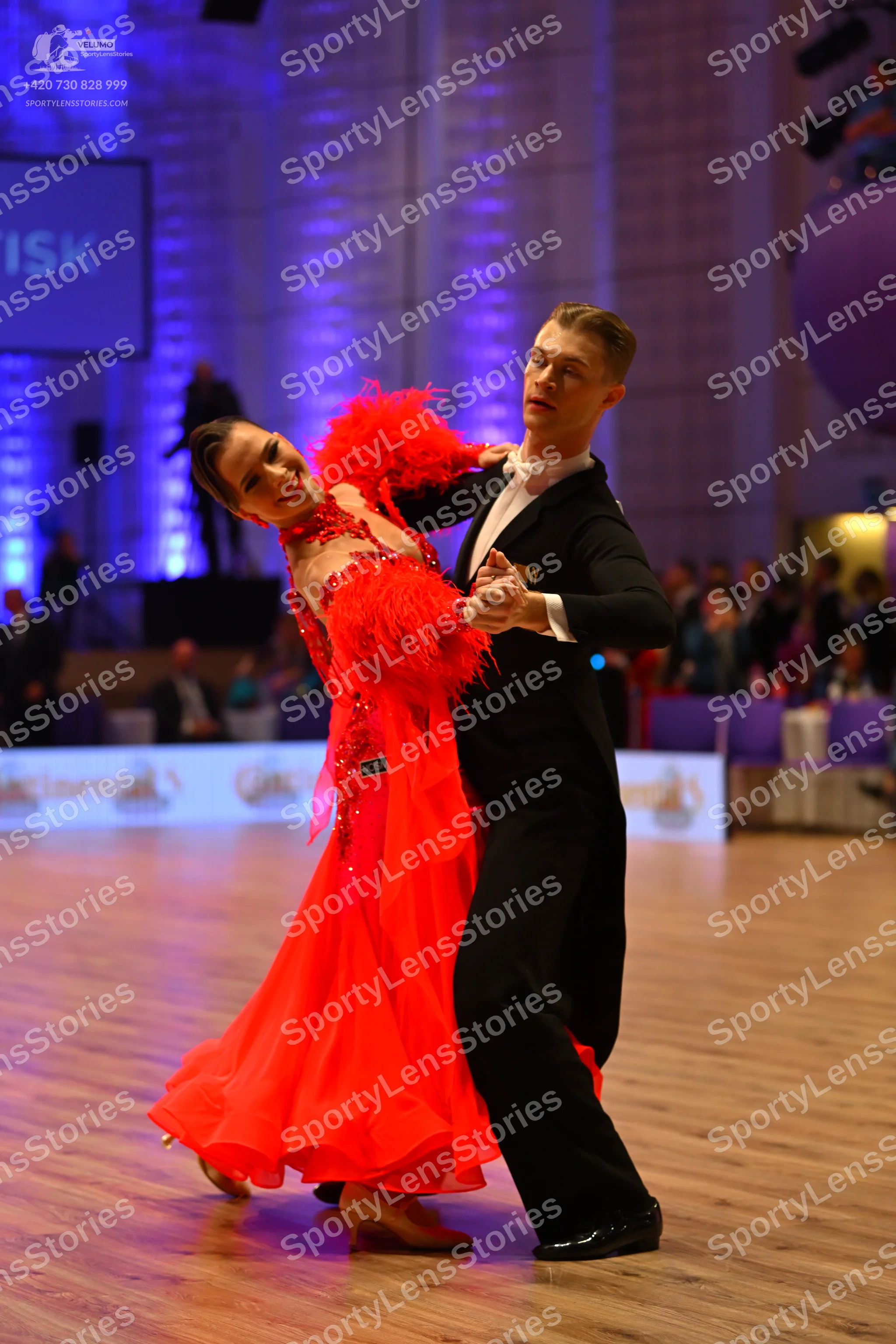 Dancesport competitor: Female dancer: red Latin dress with feather-like accents on the bodice