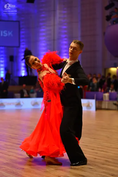 Dancesport competitor: Female dancer: red Latin dress with feather-like accents on the bodice