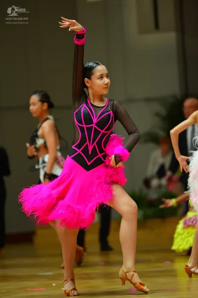 Dancesport competitor: Female dancer in foreground: pink and black Latin dance dress with long sheer bl