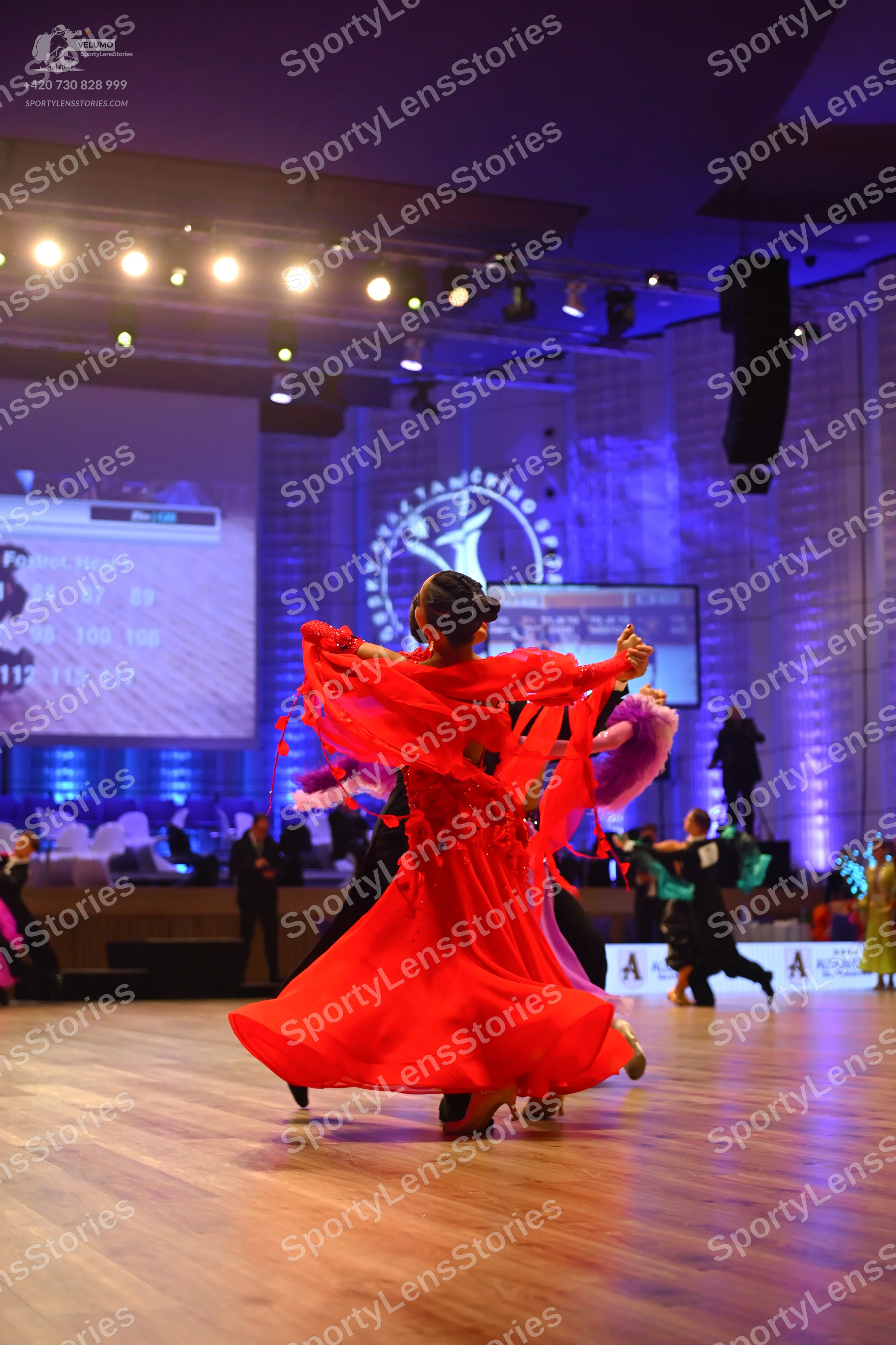 Dancesport competitor: Main female dancer: red latin dress with ruffled or fringe-like sleeves and flow