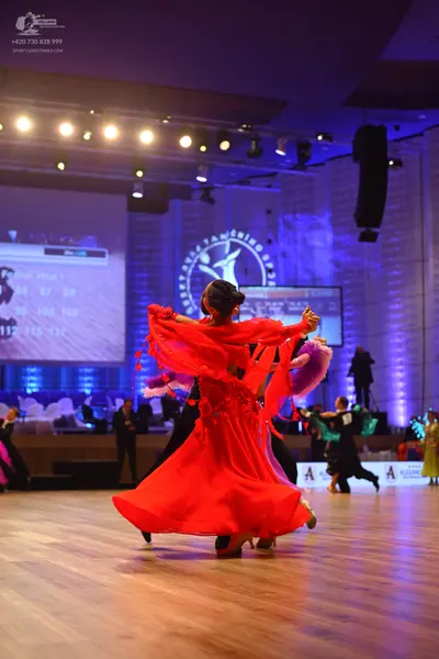 Dancesport competitor: Main female dancer: red latin dress with ruffled or fringe-like sleeves and flow