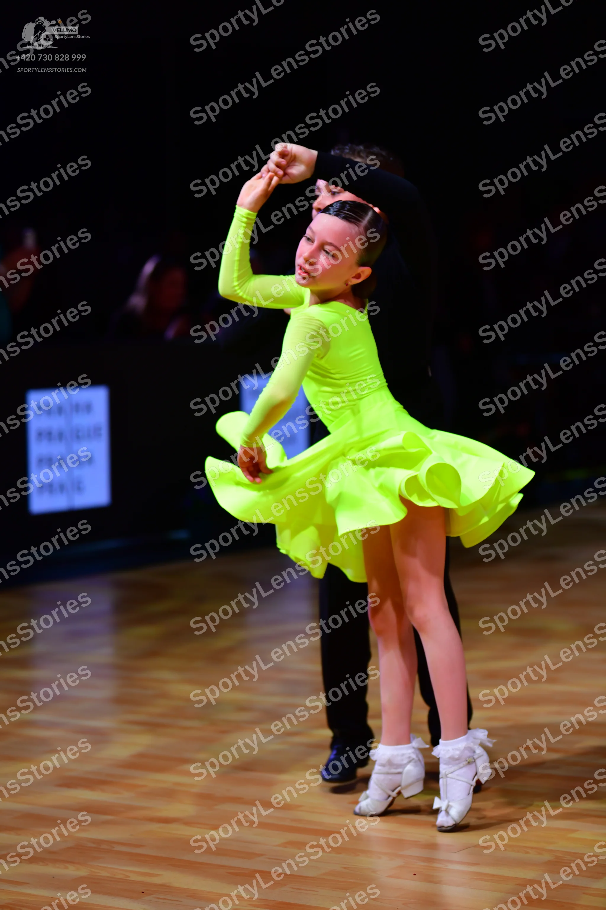 Dancesport competitor: Female dancer: bright lime green long-sleeved latin dress with a ruffled skirt