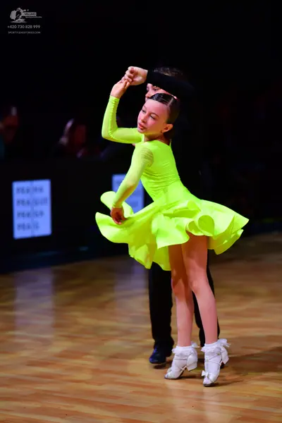 Dancesport competitor: Female dancer: bright lime green long-sleeved latin dress with a ruffled skirt
