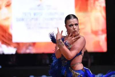 Dancesport competitor: Female dancer: Blue Latin dance dress featuring sequins, crystals, and blue feat