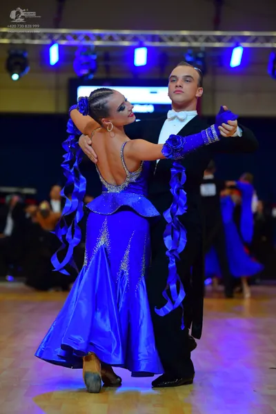Dancesport competitor: Male dancer: black formal suit, white shirt, white bow tie, and blue gloves