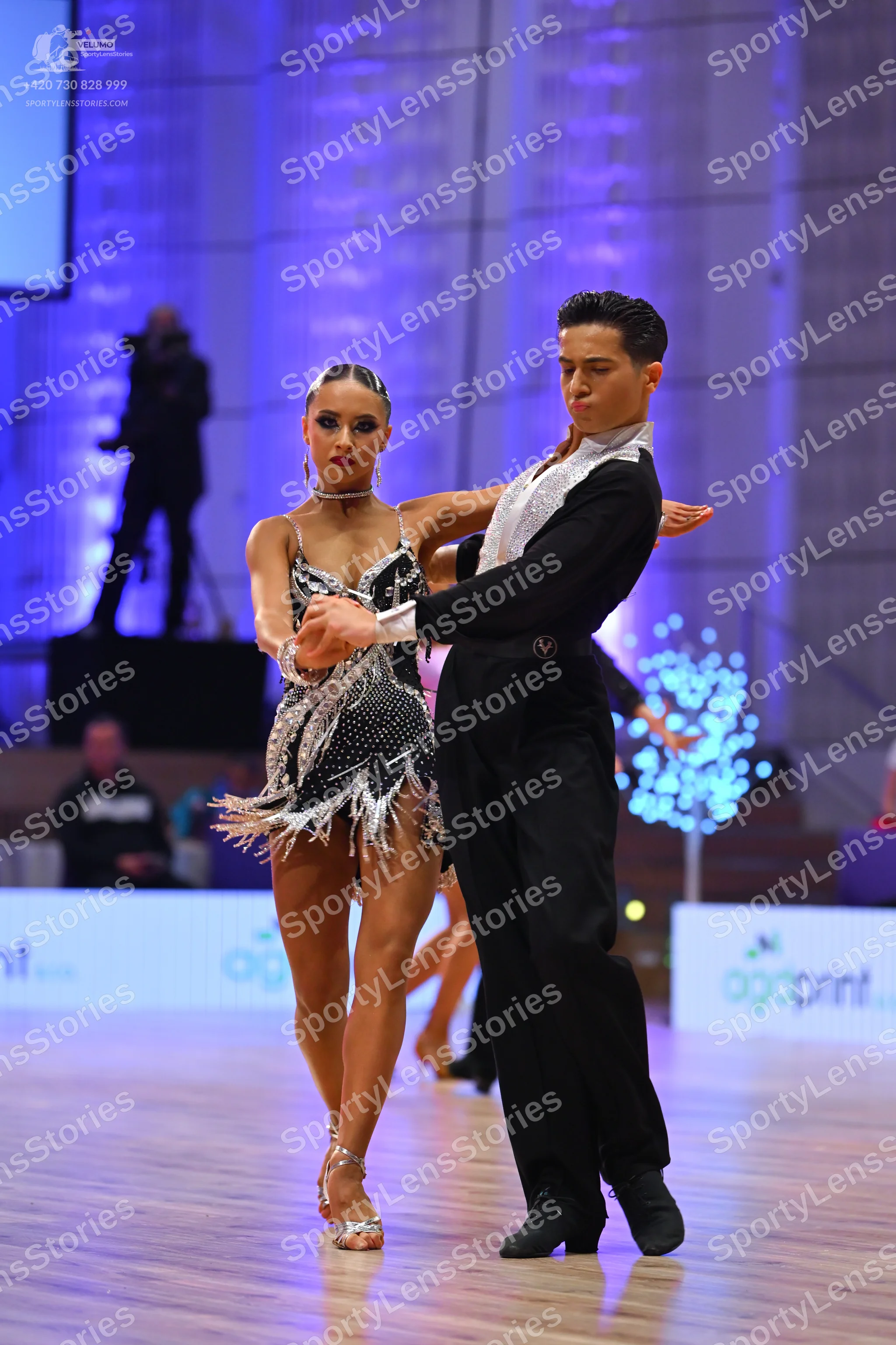 Dancesport competitor: Female dancer: silver and black sequined Latin dress with fringe and a thin chok