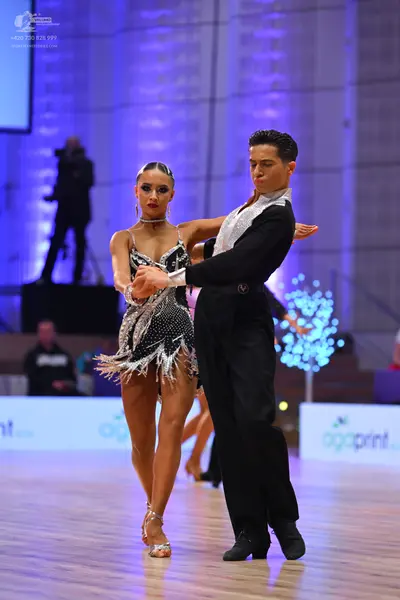 Dancesport competitor: Female dancer: silver and black sequined Latin dress with fringe and a thin chok