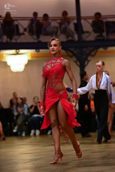 Dancesport competitor: Female dancer: red latin dress with lace and mesh strap details, featuring a hig