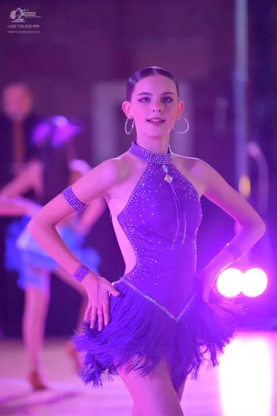 Dancesport competitor: Female dancer: purple latin dress with sequins, halter neck, side cutouts, and a
