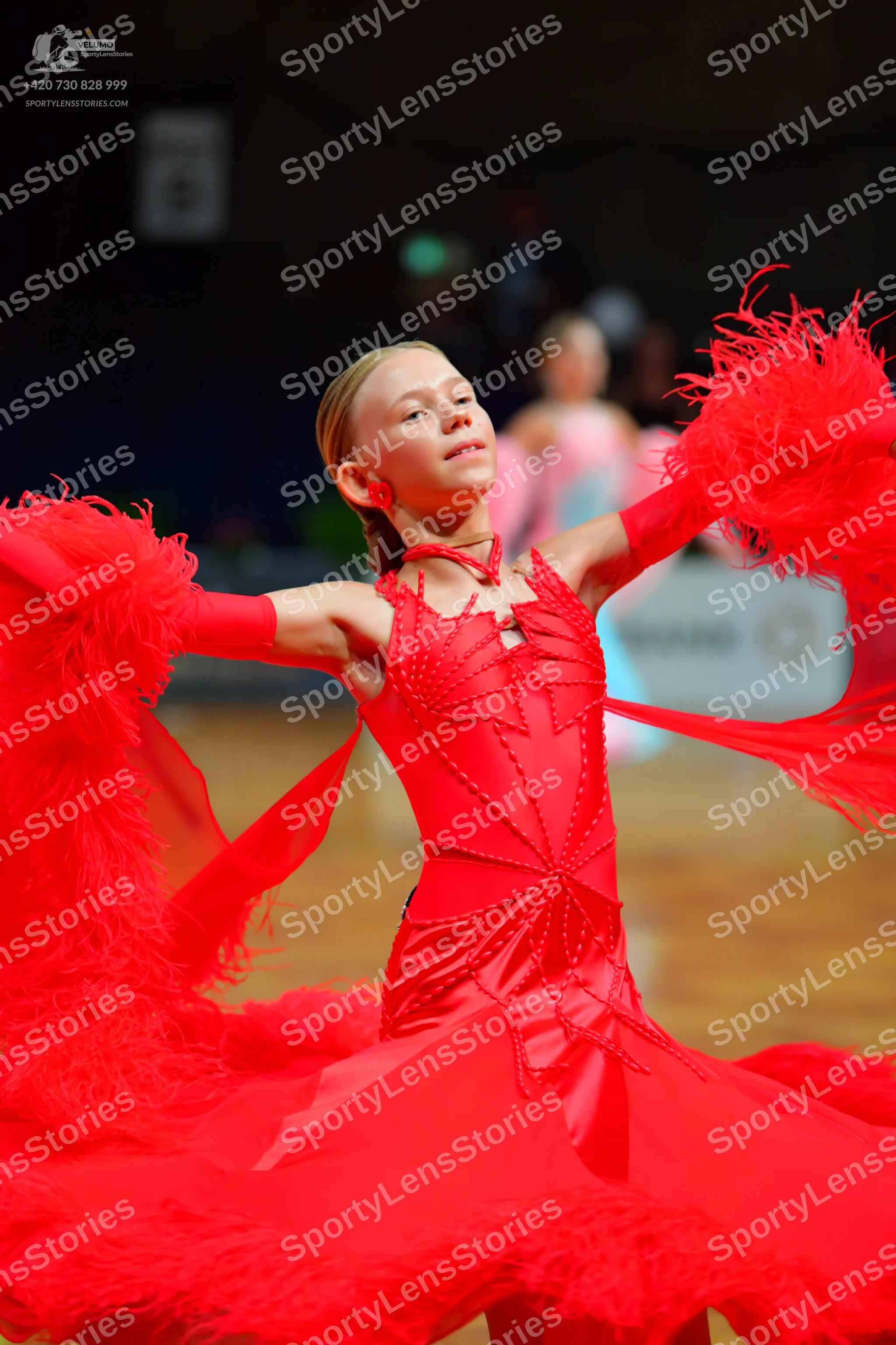 Dancesport competitor: Female dancer (foreground): bright red Latin dance dress with satin-like fabric,