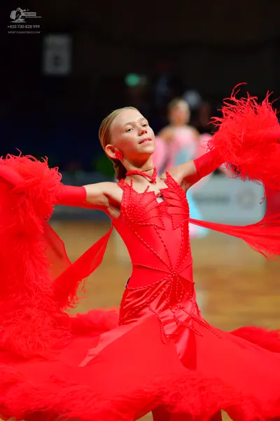 Dancesport competitor: Female dancer (foreground): bright red Latin dance dress with satin-like fabric,