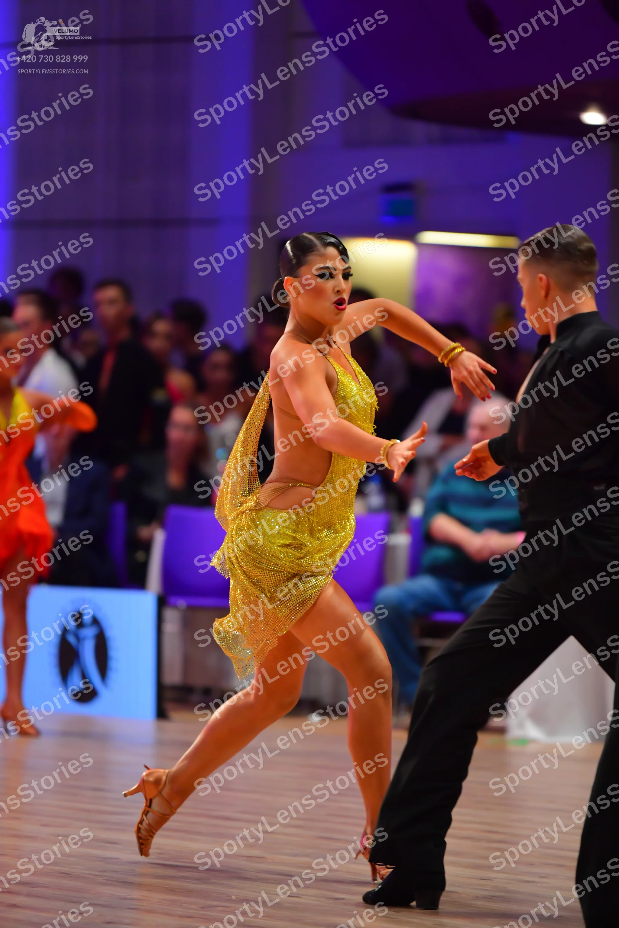 Dancesport competitor: Female dancer: gold sequined latin dress with thin straps and a high slit