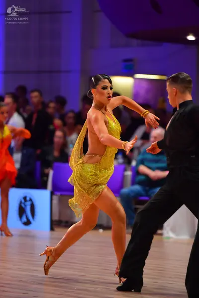 Dancesport competitor: Female dancer: gold sequined latin dress with thin straps and a high slit