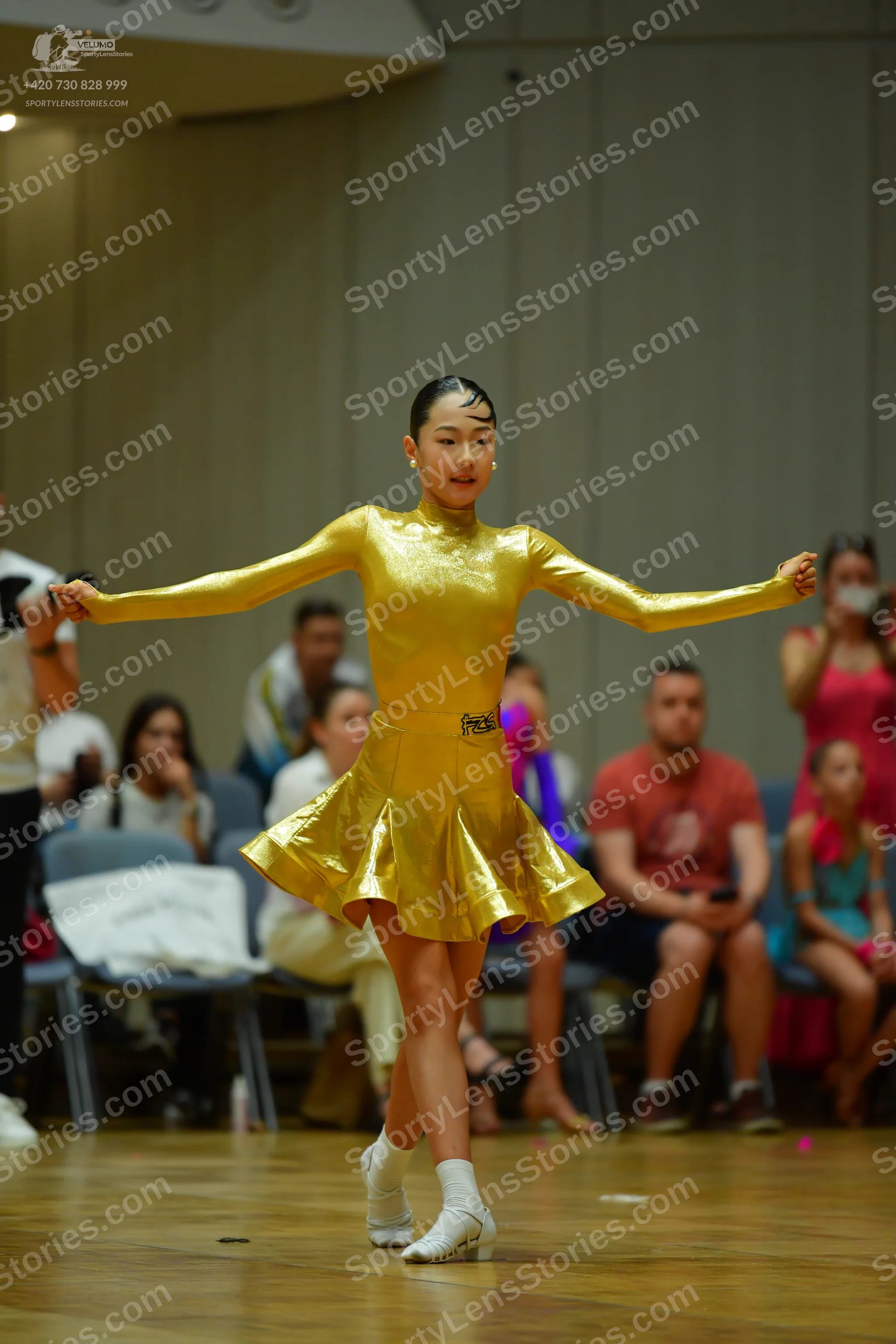 Dancesport competitor: Female dancer: gold metallic long-sleeved dress with a flared skirt