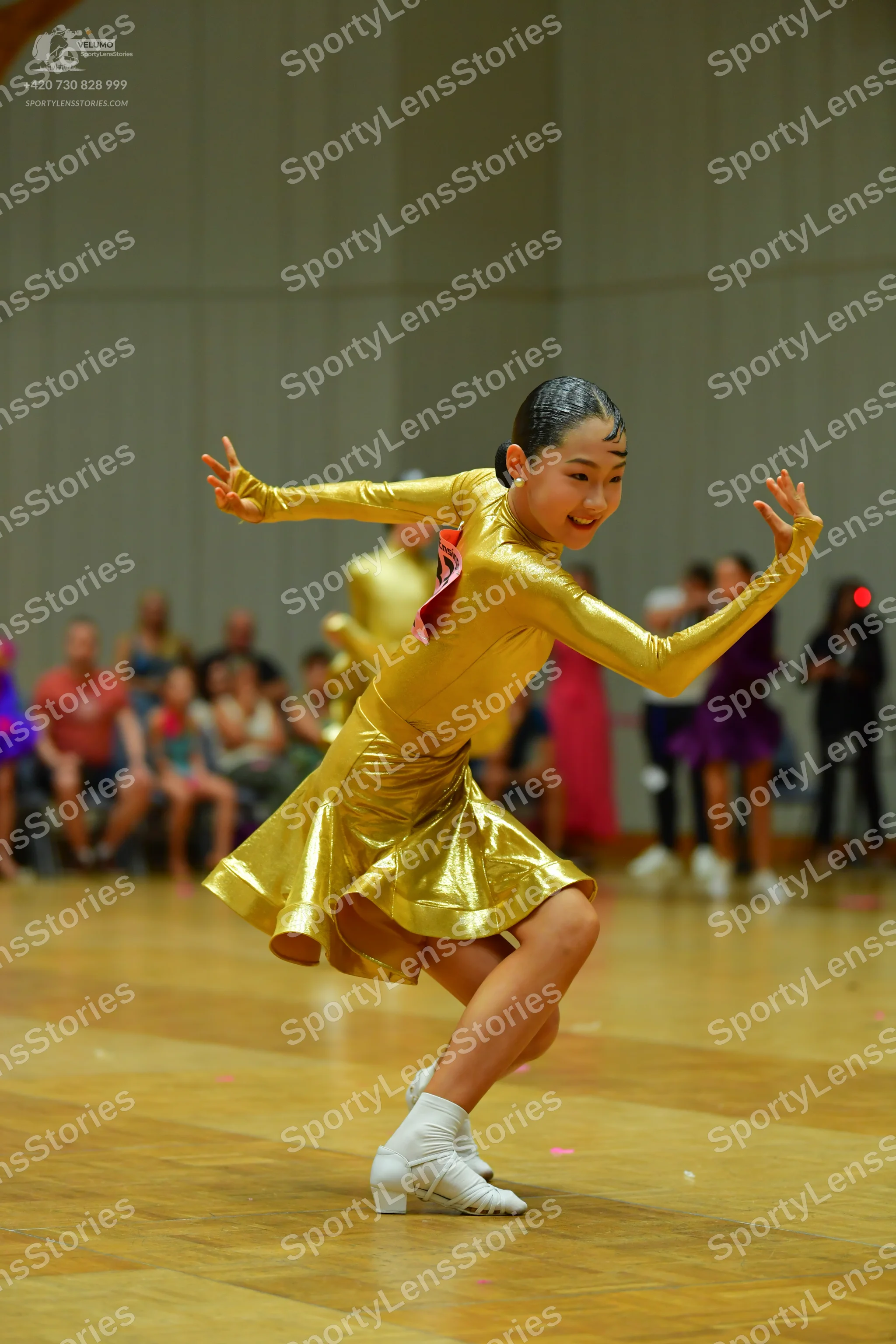 Dancesport competitor: Female dancer: gold metallic long-sleeved latin dress with a short skirt