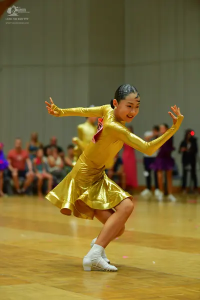 Dancesport competitor: Female dancer: gold metallic long-sleeved latin dress with a short skirt