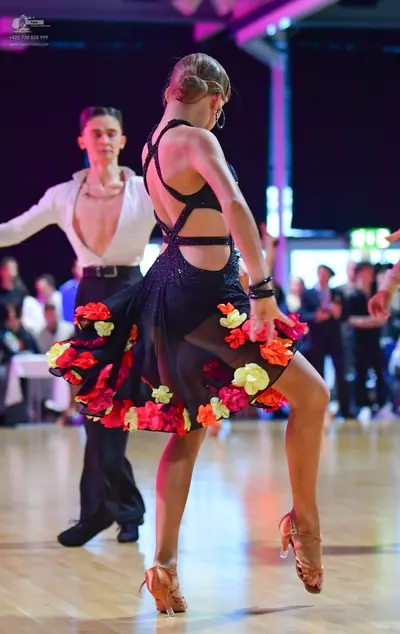 Dancesport competitor: Male dancer: white long-sleeved shirt with an open collar, black trousers, and a
