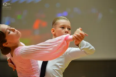 Dancesport competitor: Female dancer: light pink dress with long, pleated sleeves and a textured bodice