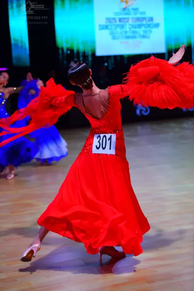 Dancesport competitor: Female dancer: red ballroom gown with a sequined bodice and large, voluminous, r