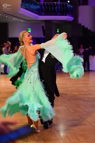 Dancesport competitor: Female dancer: mint green ballroom dress with large flowing sleeves, heavily tex