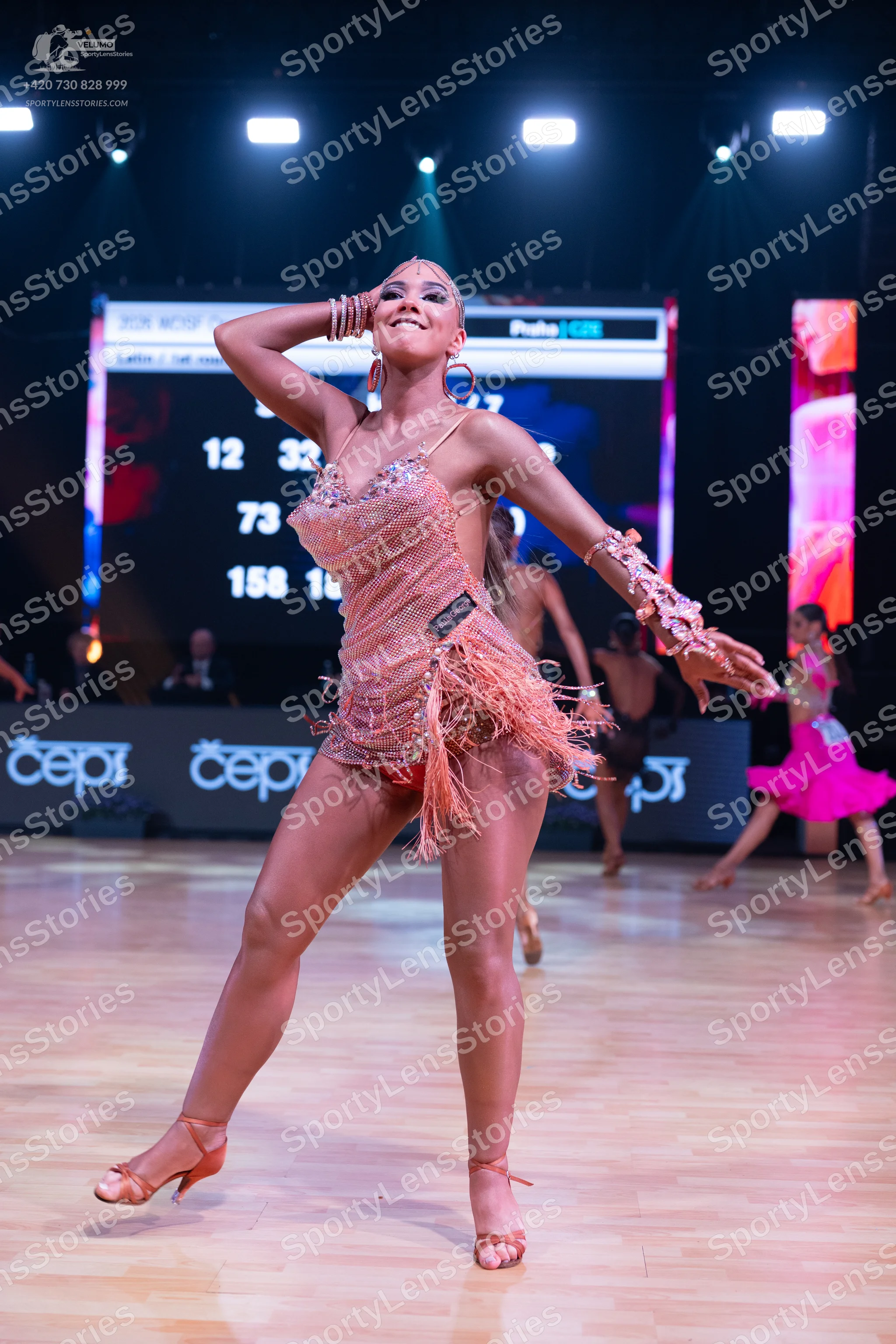 Dancesport competitor: Female dancer in foreground: nude-colored sequined Latin dance dress with long f